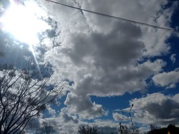 Low angle view of bare trees against cloudy sky