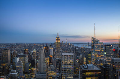 Modern buildings in city against sky during sunset