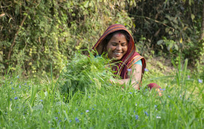 Portrait of a smiling young woman wearing sari working at agricultural field in rural india