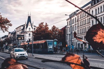 Cars on city street by buildings against sky