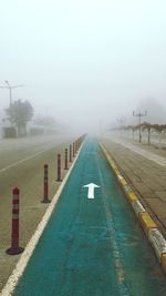 Footpath by road against sky during foggy weather