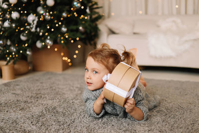 Young woman using mobile phone while sitting on christmas tree