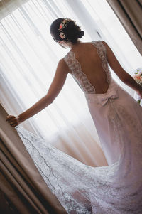 Rear view of bride standing by window