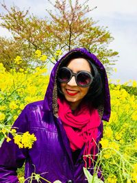 Portrait of smiling woman in sunglasses and purple jacket amidst plants