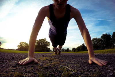 Low section of man exercising on road during sunset