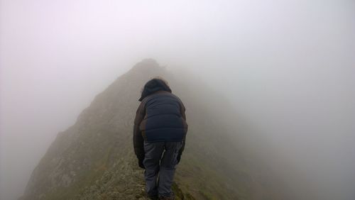 Rear view of people walking on mountain during winter