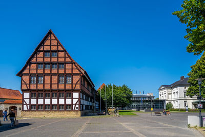 Road by buildings against blue sky