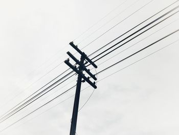 Low angle view of silhouette electricity pylon against sky