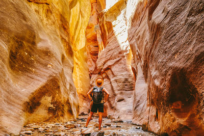 Young man wearing a hat, exploring a slot canyon in kanarra fall, utah