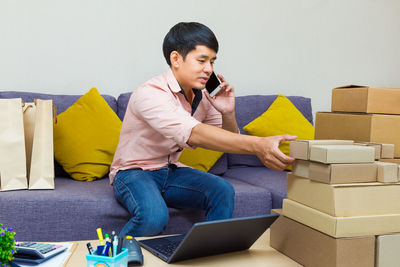 Young man using mobile phone while sitting on sofa