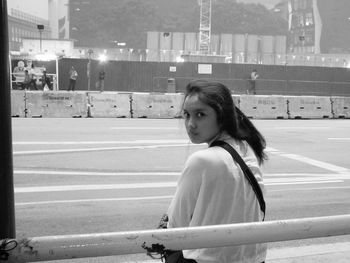 Portrait of young woman sitting at bus stop