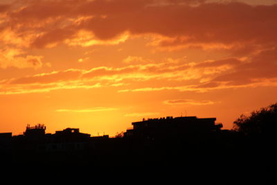 Silhouette buildings against sky during sunset