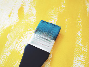 High angle view of paintbrush on yellow fabric