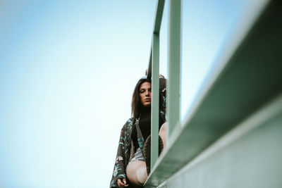 Low angle portrait of woman standing against clear sky