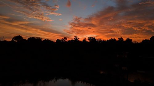 Silhouette trees by lake against sky during sunset