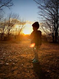 Optical illusion of boy holding sun against sky during sunset