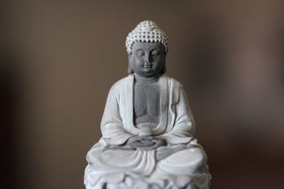 Close-up of buddha statue against plain background