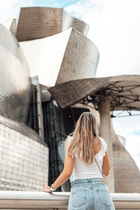 Rear view of woman standing against building