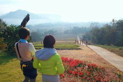 Rear view of people standing on flower field