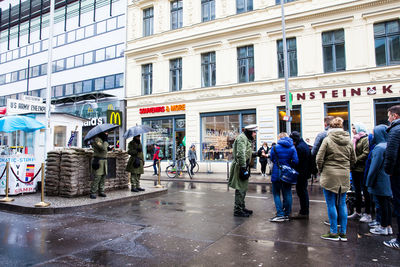 People walking on wet street in city during rainy season