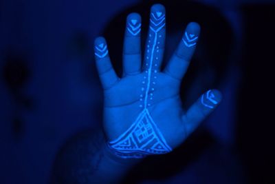 Cropped image of hand with henna tattoo in darkroom