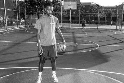 Full length portrait of young man standing on basketball court