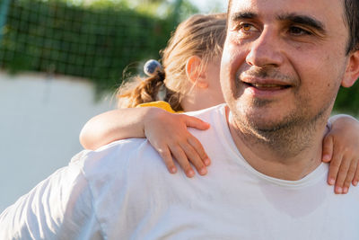 Happy father carrying daughter on back at sports ground