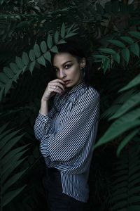 Young man looking away while standing against plants