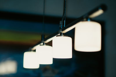 Close-up of illuminated lighting equipment hanging on metallic rod