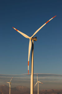 Low angle view of wind turbines against sky