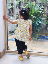 Rear view of boy standing against wall