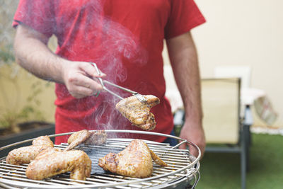 Midsection of man preparing food on barbecue grill