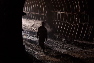 Rear view of silhouette man walking in tunnel