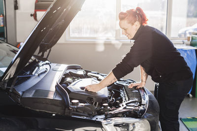 Female mechanic repairing car in auto repair shop