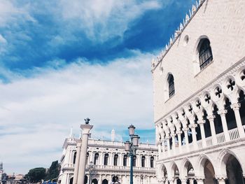 Low angle view of old buildings against cloudy sky