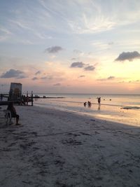 People on beach against sky during sunset