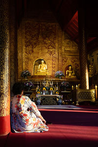 Rear view of a buddha statue against building