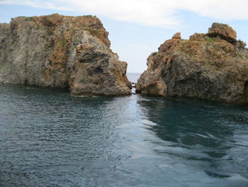 Rock formation in sea against sky