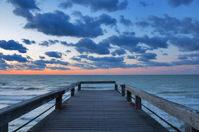 Pier over sea against sky during sunset