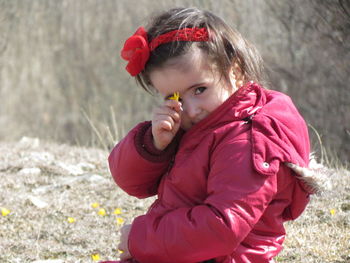 Portrait of girl showing flower on field