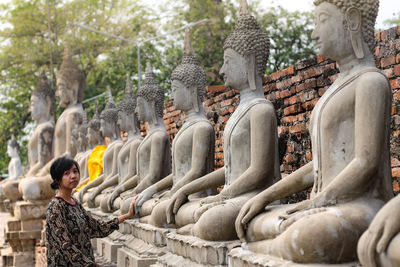 Portrait of mid adult woman standing by buddha statues