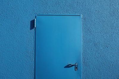 Close-up of closed door on blue wall
