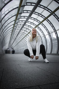 Low angle view of woman crouching on footbridge