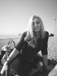 Portrait of smiling woman sitting against sky during sunny day