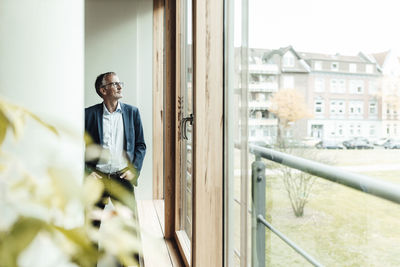 Portrait of smiling man standing against window