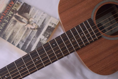 High angle view of guitar with book on bed