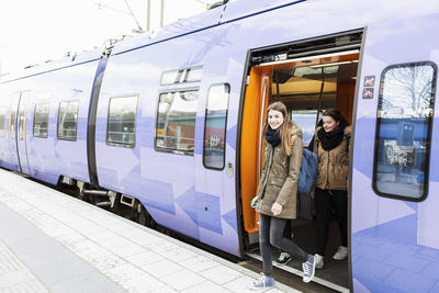 Happy young women disembarking train