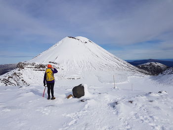 Rear view of man on snowcapped mountain against sky