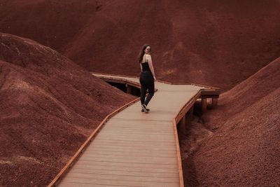 Woman walking on boardwalk amidst mountains