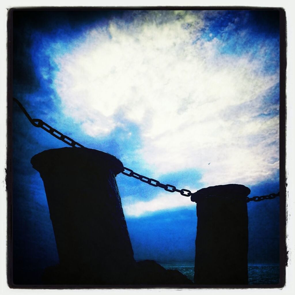 low angle view, sky, blue, transfer print, auto post production filter, cloud - sky, pole, metal, electricity, cloud, safety, power supply, connection, day, outdoors, no people, fuel and power generation, silhouette, built structure, protection